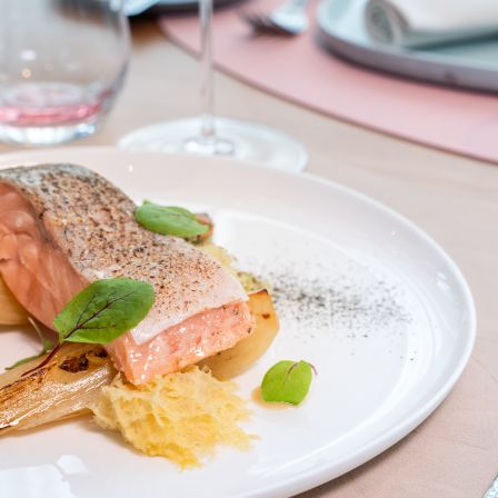 Delicately served salmon fillet on roasted potatoes and vegetable garnish.