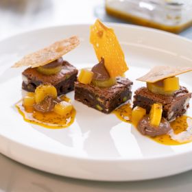 Elaborate dessert platter with decorated chocolate brownies with passion fruit sauce.